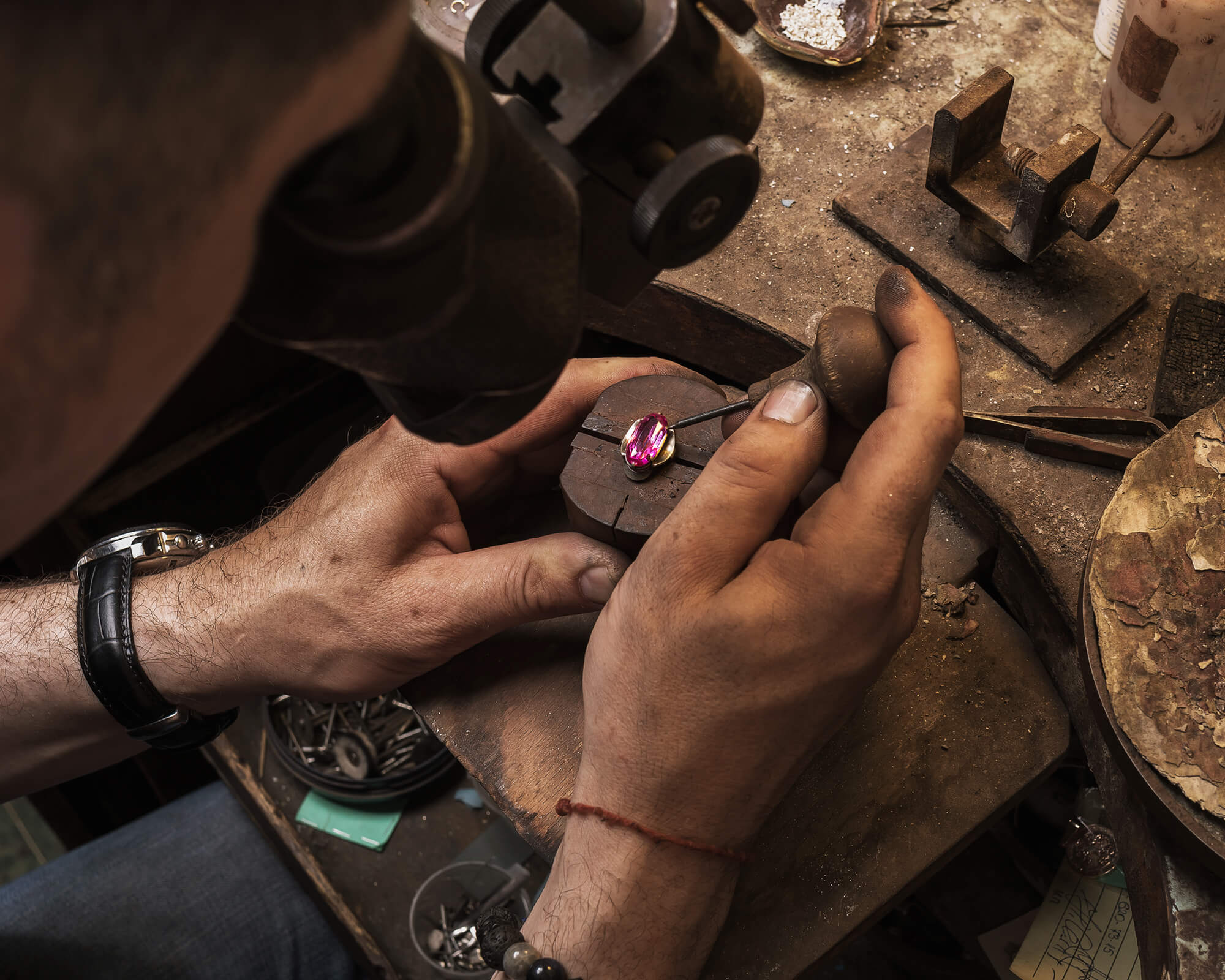 Jeweler setting pink gemstone into gold ring 